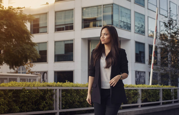Beautiful hispanic business woman in suit walking outside with her office on a background golden hour, horizontal image, copy space - Fotografie, Obrázek