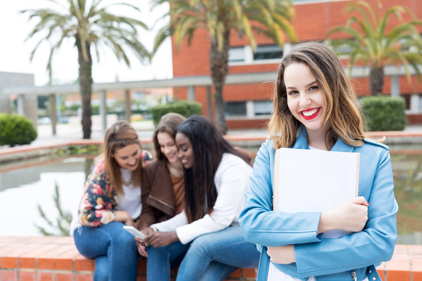 Uśmiechający się student pozowanie z książek w kampusie Uniwersytetu - Zdjęcie, obraz