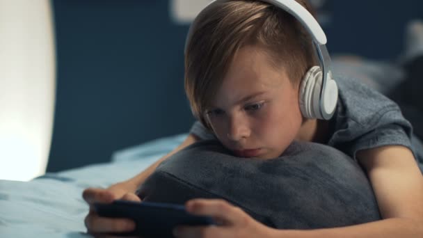 Boy playing smartphone on bed - Footage, Video