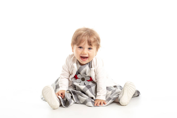 Elegant Happy baby girl 1 year old sitting on the studio floor. White Background. Concept Happiness. - Photo, Image