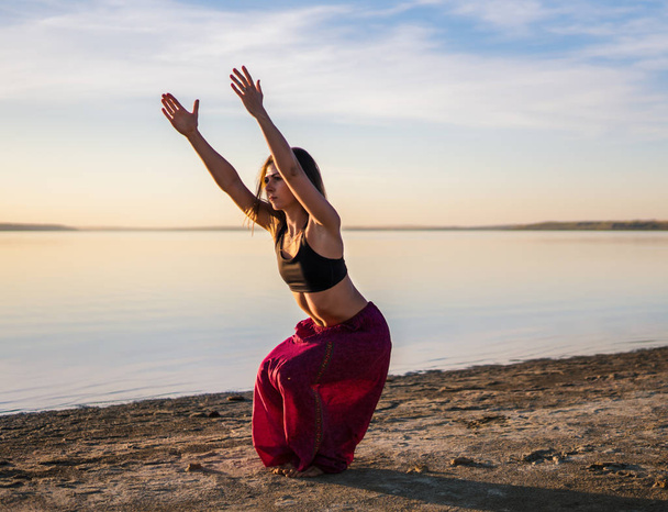 Silhouette yoga woman on the beach at sunset. - Zdjęcie, obraz