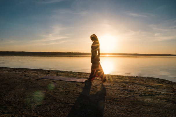 Sziluettjét jóga nő a tengerparton naplementekor. - Fotó, kép