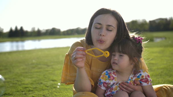 Μαμά και κόρη της ειδικής φυσώντας φυσαλίδες στο πάρκο - Πλάνα, βίντεο