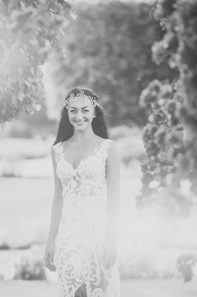 Wedding organization. Happy girl bride smiling in wedding tiara and white dress - Fotó, kép