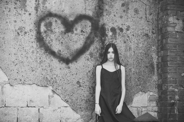 Love hurts. Girl posing with heart graffiti on grey wall - Fotografie, Obrázek