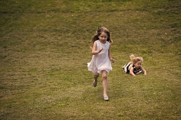 Kids playing - happy game. Kids run and fall on green grass on summer day - Zdjęcie, obraz