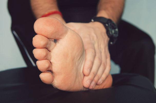 Το χέρι του ανθρώπου που μασάζ ένα πόδι. Ο άνθρωπος με την οδυνηρή και φλεγμονώδες ουρική αρθρίτιδα στο πόδι του γύρω από την περιοχή του μεγάλο δάχτυλο του ποδιού. - Φωτογραφία, εικόνα