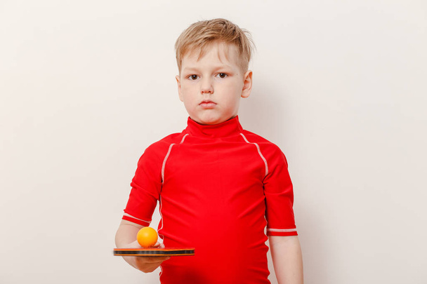 boy in red t-shirt holding table tennis racket and ball on white background - Foto, Bild