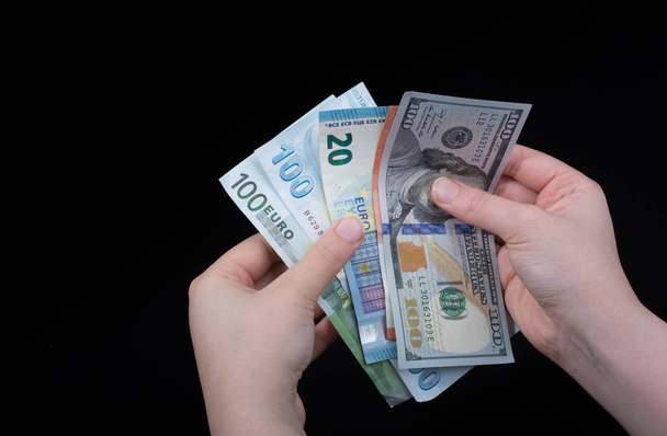 Hand-holding Amerikaanse dollar bankbiljetten geïsoleerd op zwarte achtergrond - Foto, afbeelding