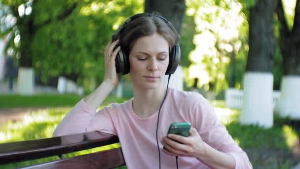 young stylish beautiful woman, on city streets listening to music in large monitor headphones. - Filmmaterial, Video