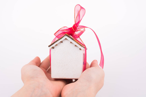 Рука тримає модель будинку з рожевою стрічкою
 - Фото, зображення