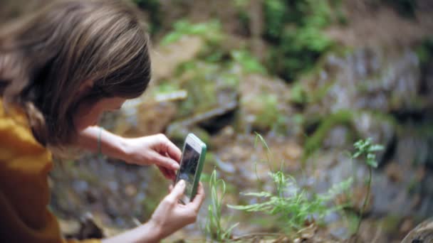 Travel adventure woman taking photos of a smartphone on a mountain waterfall, enjoying the beautiful scenery of nature - Materiał filmowy, wideo