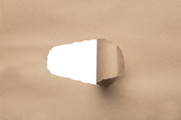 holes in brown paper with torn sides over paper background with space for text. - Photo, Image
