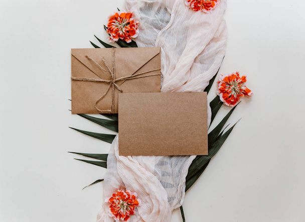 Wedding invitation card. Greetings card with craft envelope and flowers flat lay - Фото, зображення