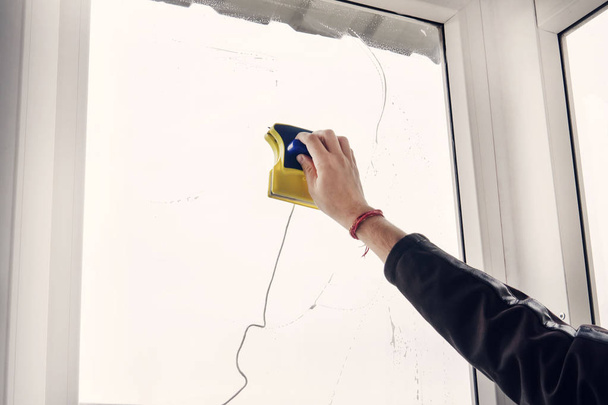 Window cleaner using a squeegee to wash a window. Washing the window with a magnetic brush. Simultaneous cleaning of the window on both sides. - Photo, Image