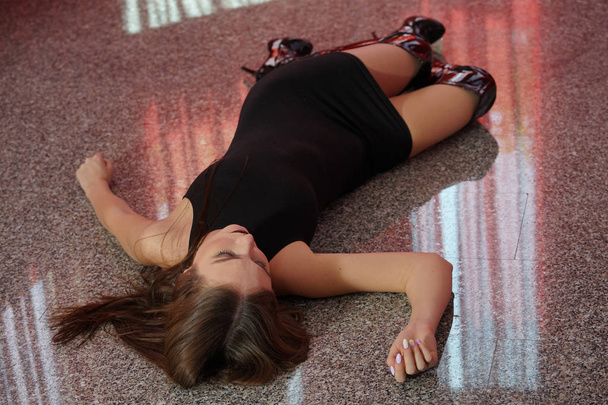 Crime scene - female victim lying on the floor in short dress and boots - Photo, Image