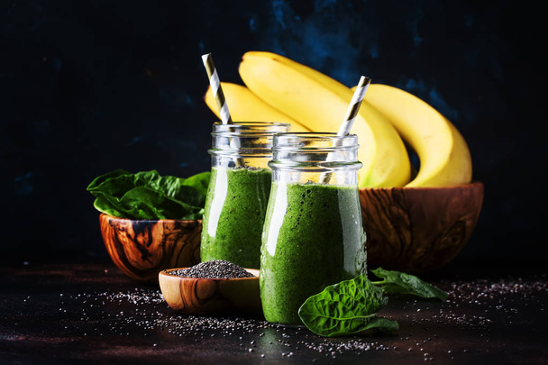 Healthy detox green smoothies with spinach, banana and chia seeds, brown background, selective focus - Photo, Image