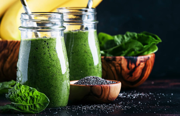 Healthy detox green smoothies with spinach, banana and chia seeds, brown background, selective focus - Photo, image