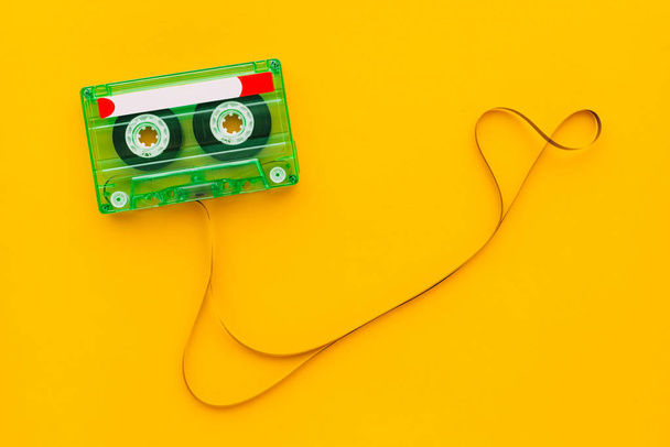 Top view of audio cassette with tangled tape on bright yellow background with copy space, minimalistic composition - Photo, Image