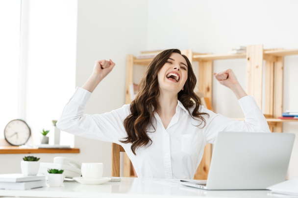 Successful business woman with arms up sitting in modern office. - Foto, Imagem