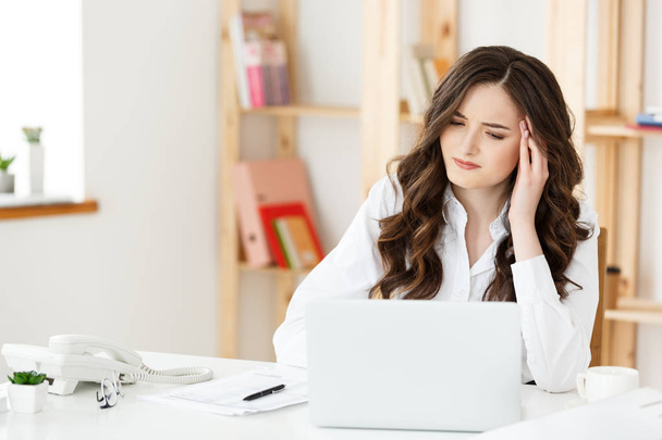 Unavená mladá podnikatelka trpící dlouhou dobu sedí u počítače stolu v kanceláři - Fotografie, Obrázek