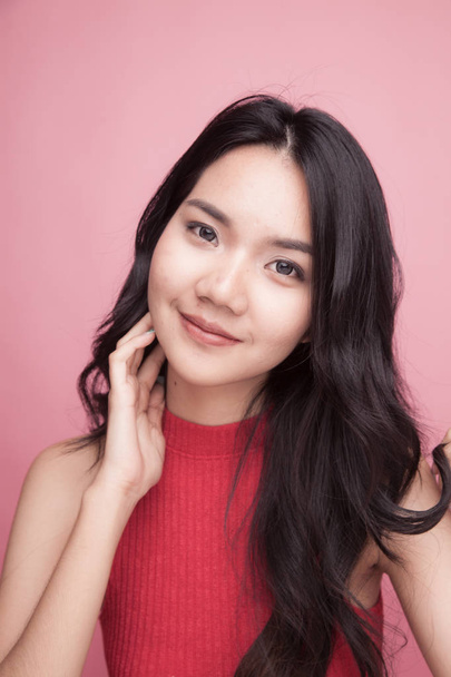 Portrait of beautiful young Asian woman in red shirt on pink background - Photo, image