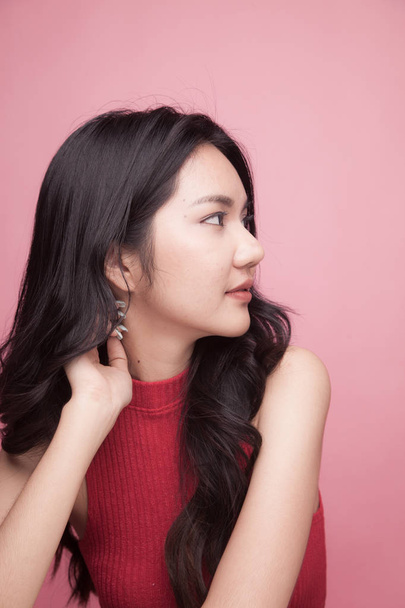 Portrait of beautiful young Asian woman in red shirt on pink background - Photo, Image