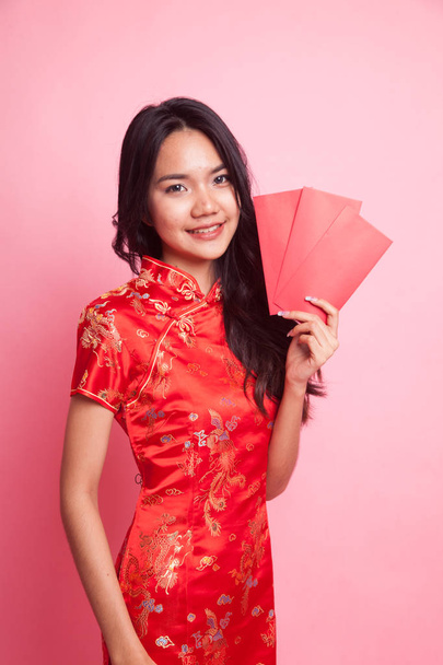 Cute Asian girl in chinese red cheongsam dress with red envelope  on pink background - Foto, imagen