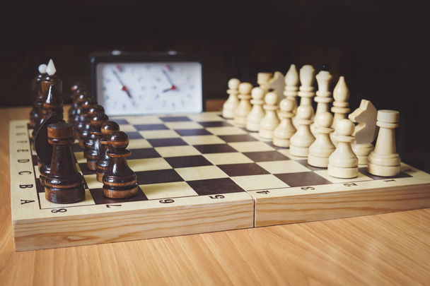 Schaakspel, schaakbord en schaakstukken klok close-up. In de afbeelding is er een koning, een koningin en een toren. Het begin van het schaakspel. eerste stap - Foto, afbeelding