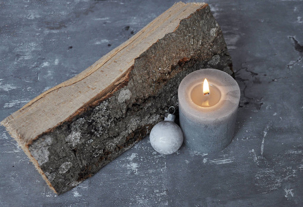 Burning candle, Christmas tree bauble and wood billet on concrete - Photo, image