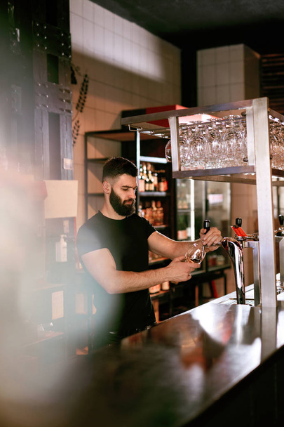 Cantinero trabajando en Bar Pub. Hombre guapo vertiendo cerveza de barril en vidrio. Alta resolución
. - Foto, Imagen