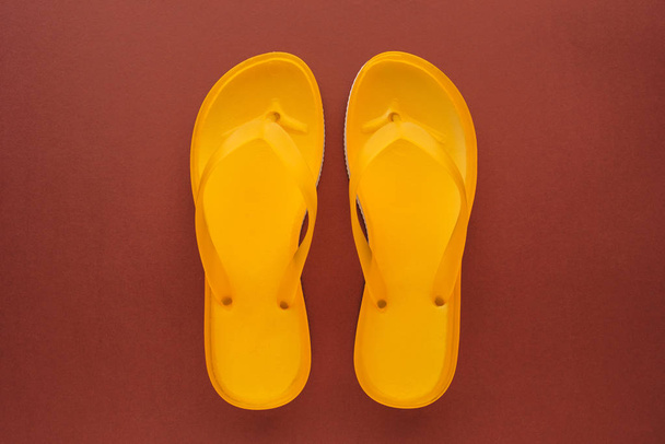 Yellow beach flip flops on brown background, top view - Foto, immagini