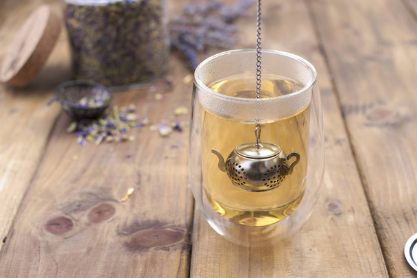 Een glas met thee, gedroogd van thee in een kruik. Houten achtergrond en vrije ruimte voor tekst of kaarten. , kopiëren van ruimte - Foto, afbeelding