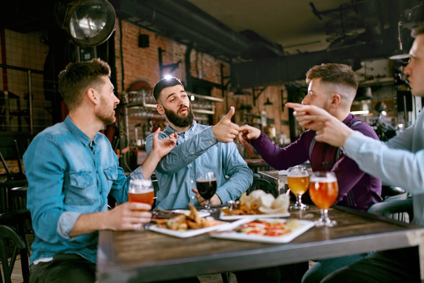 Friends At Dinner Drinking Beer And Eating Food In Pub Restaurant. High Resolution. - 写真・画像