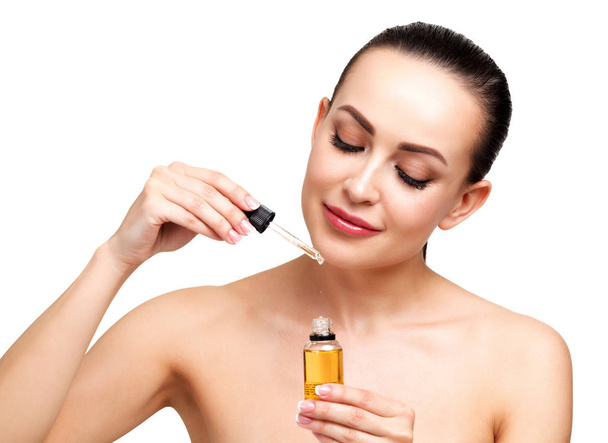 ピペットの若い女性の顔に適用する化粧品のオイルのクローズ アップ ショット。美容療法の概念を。白い背景に分離 - 写真・画像