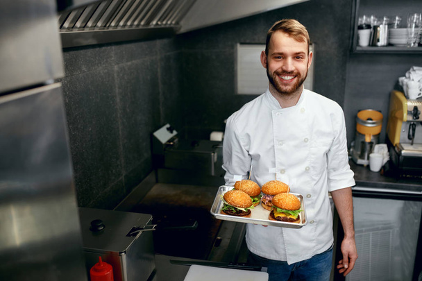 Smiling Chef With Burgers In Modern Restaurant Kitchen. High Resolution. - Zdjęcie, obraz
