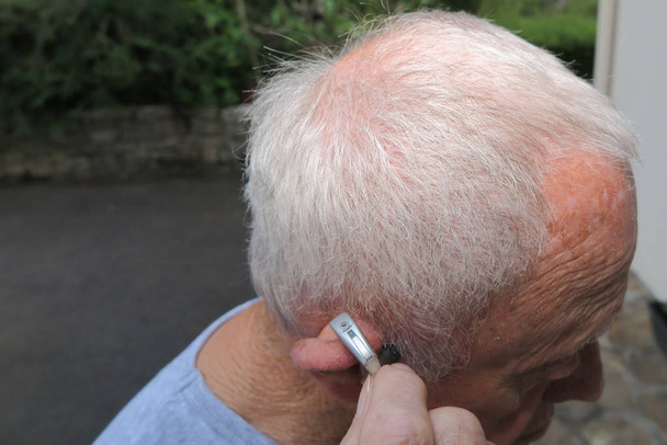 Modern digital in the ear hearing aid for deafness and the hard of hearing in aged man senior ear outdoor - Photo, Image