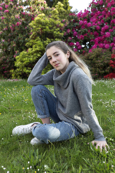šestnáctiletý teenager sedí v parku s trávou a květinami, v Limoges, Francie. - Fotografie, Obrázek