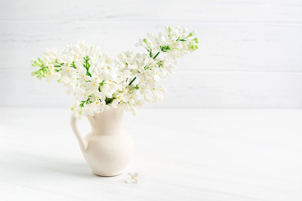 Цвітіння білого бузку в керамічній вазі (jar) на фоні білого столу з пробілом для копіювання
 - Фото, зображення