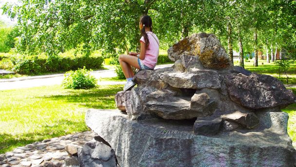 Rest in the amusement Park.Girl sitting on the bark of stones. - Photo, image