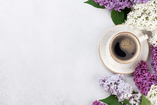 Colorful lilac flowers and coffee cup over stone background. Top view with space for your text - Photo, Image