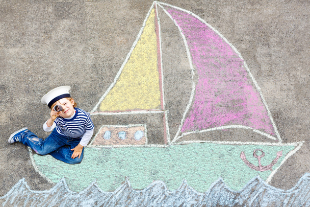 Little kid boy having fun with ship picture drawing with chalk - Foto, imagen