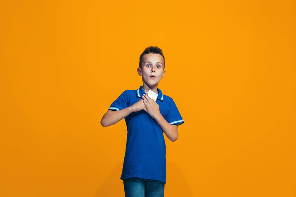 The happy teen boy standing and smiling against orange background. - Photo, image