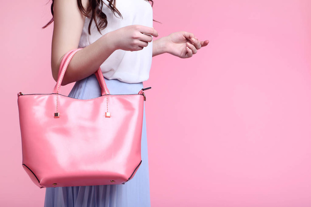 Young woman with leather handbag on pink background - Foto, immagini