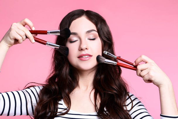 Beautiful woman with makeup brushes on pink background - Φωτογραφία, εικόνα