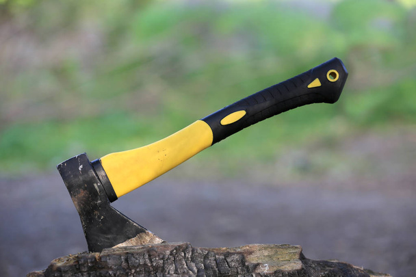 hacha con empuñadura amarilla pasiva en tronco de madera
 - Foto, Imagen