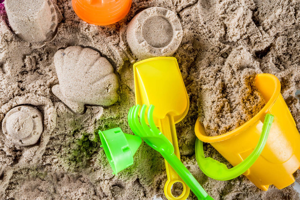 Zomer vakantie concept, kinder vakantie achtergrond, zee zand en strand helder plastic speelgoed, bovenaanzicht kopie ruimte - Foto, afbeelding