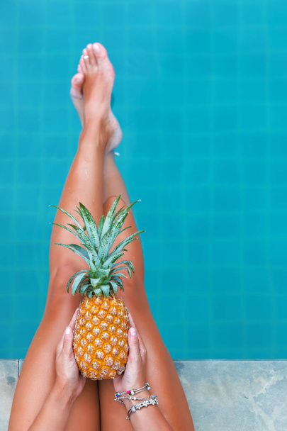 Slim woman holding pineapple fruit near swimming pool tropical e - Photo, image