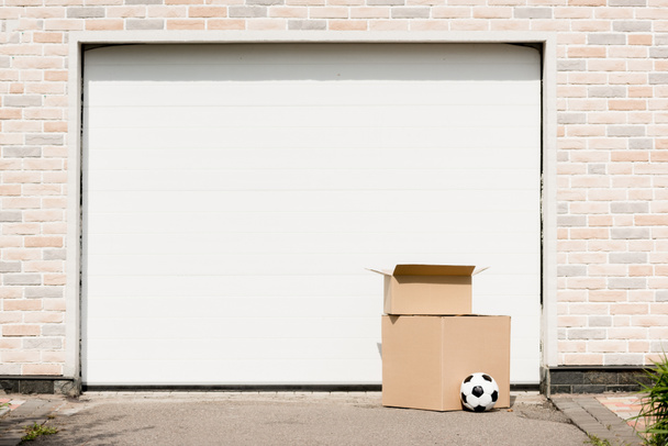 vista frontal de caixas, bola de futebol na frente do portão de garagem
 - Foto, Imagem