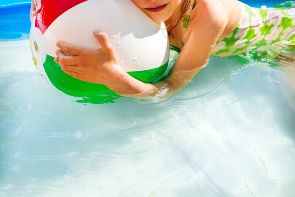 Meisje in zwembad buiten springen in het water op zomervakantie op de binnenplaats met groen spelen. Concept voor de zomervakanties, ontspanning en plezier in de zon - Foto, afbeelding